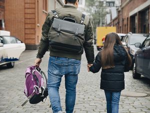 父亲和女儿walking on footpath in city