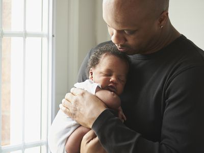 Father holding baby boy beside a sunny window