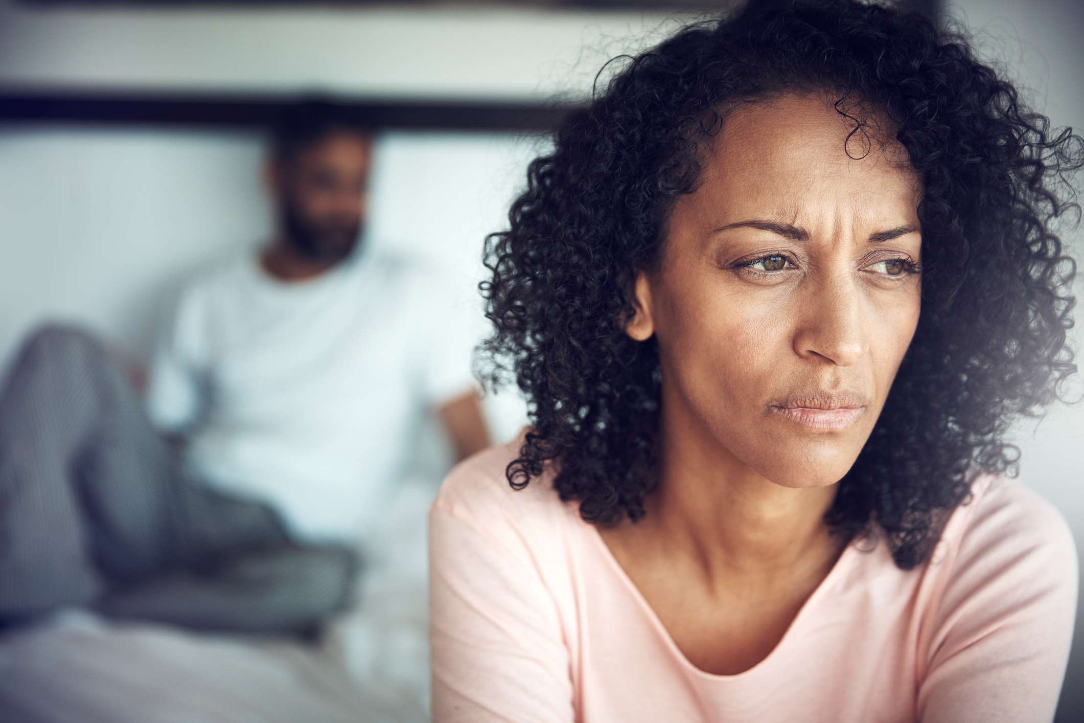 upset woman with man in background