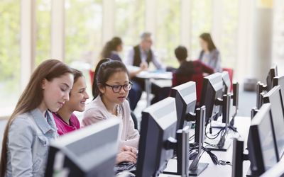 Girl students studying at computer in library