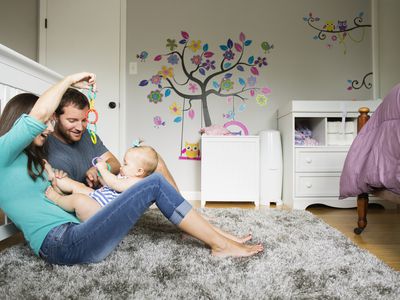 Mid adult couple playing with baby toy and baby daughter on lap