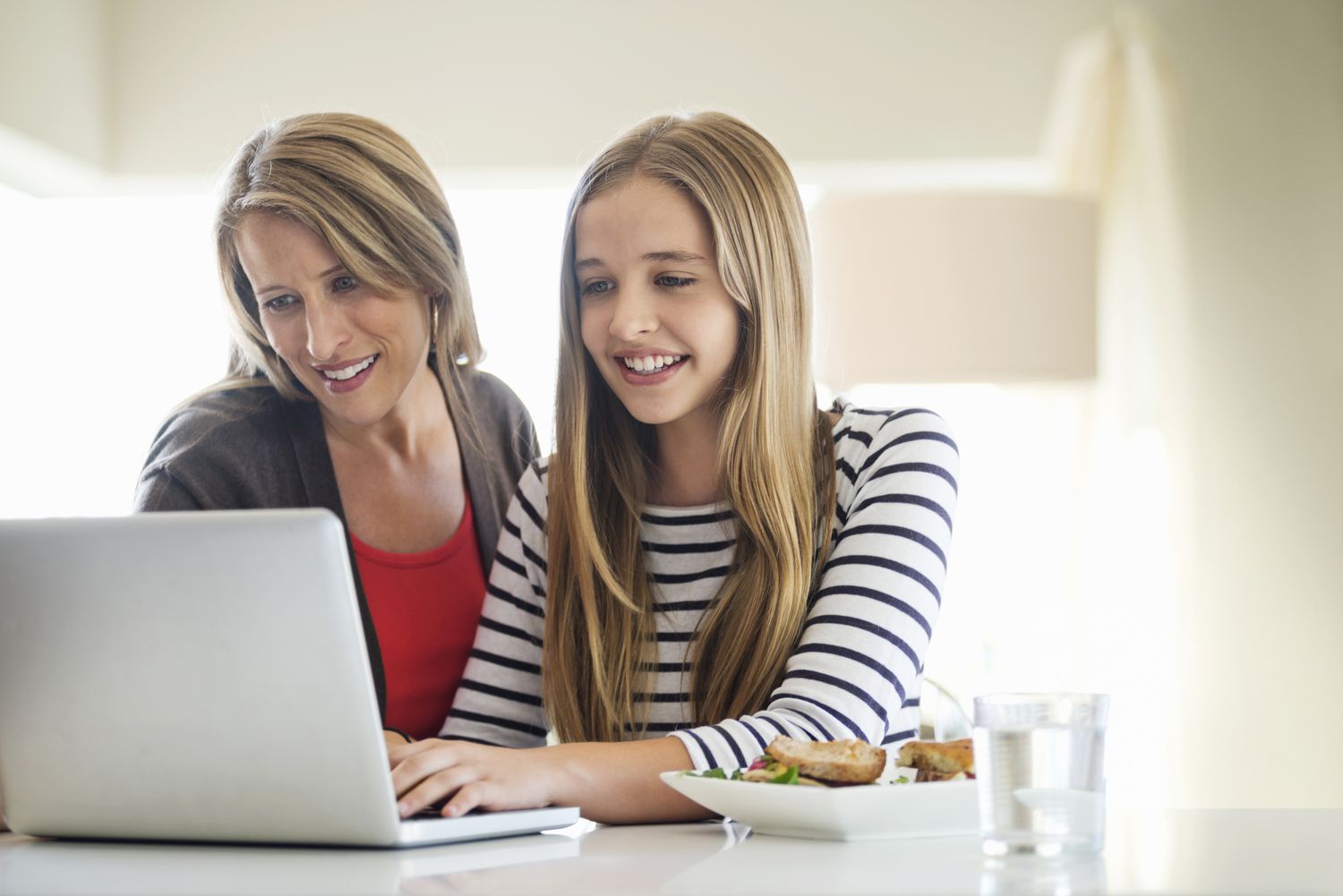 Mother and daughter using laptop together at home