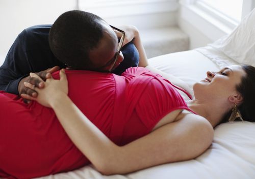 怀孕的夫妇在床上笑