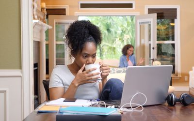 Student studying at home with parent in the background