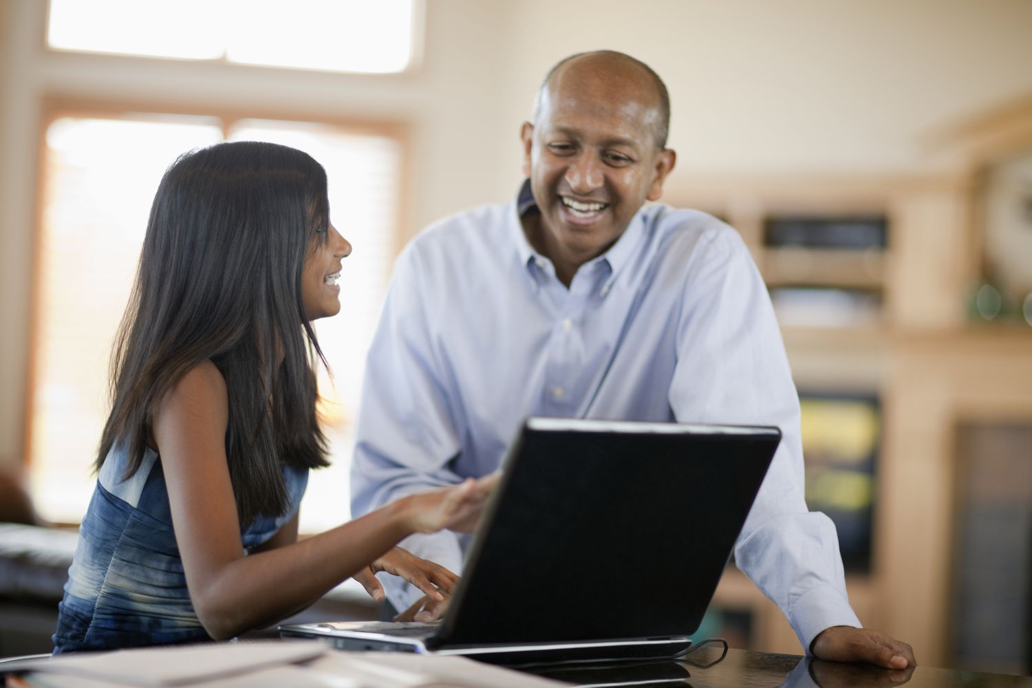 Teenage girl teaching father how to use laptop