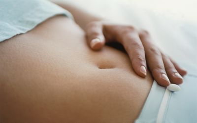 手放在女性腹部，由于过度排卵而感到浮肿和敏感
