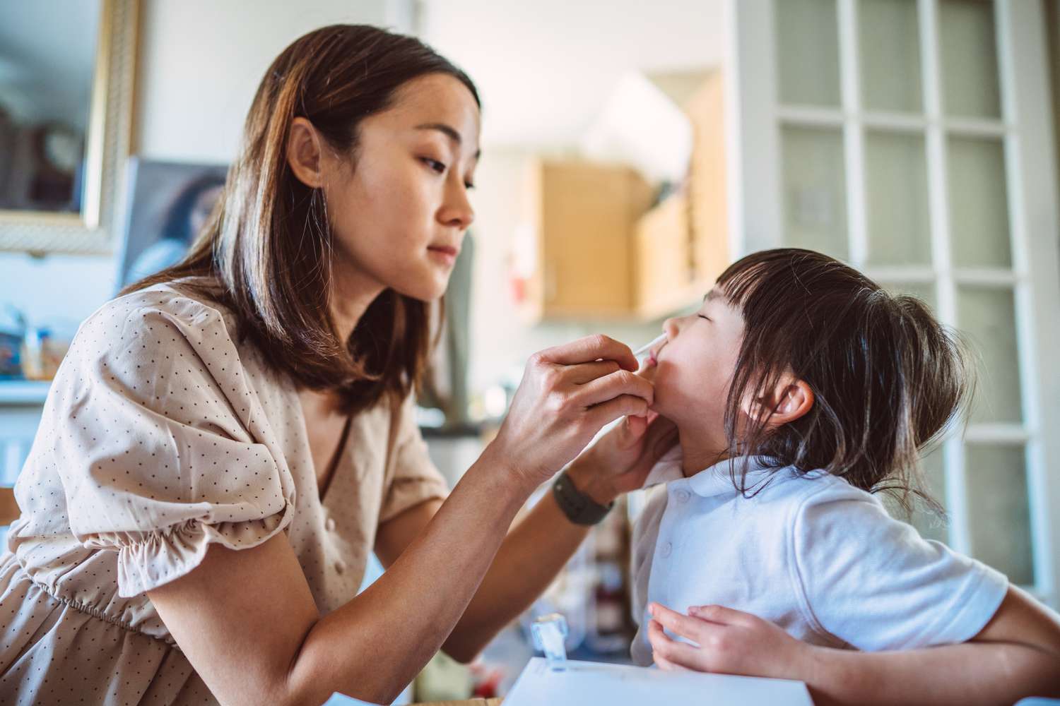 A mom using an at-home COVID-19 test on her toddler