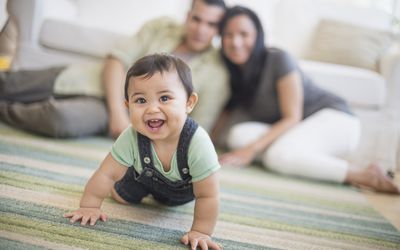 Family with baby boy crawling in living room