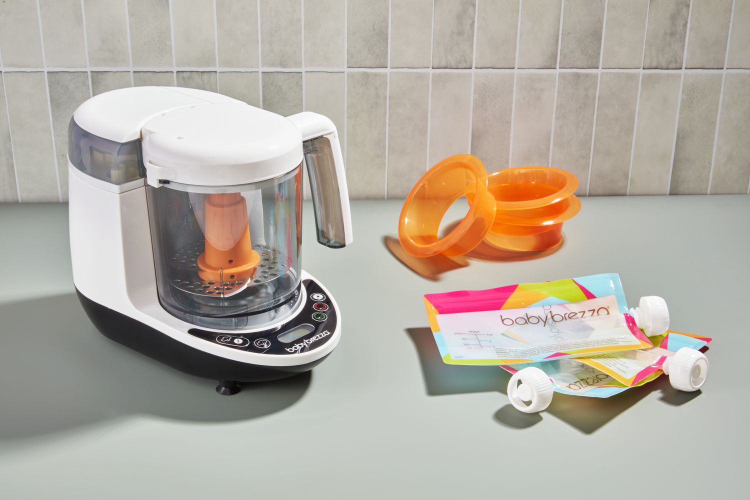 The Baby Brezza One Step Glass Baby Food Maker sits on a kitchen counter.