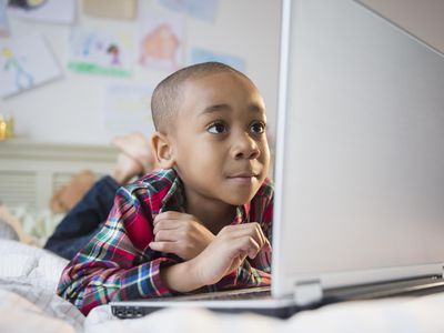 boy using laptop on a bed