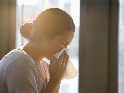 Hispanic woman wiping nose with tissue