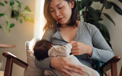 Mother breastfeeds her baby at home