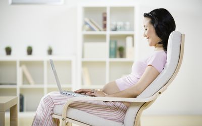 孕妇使用笔记本电脑，微笑，侧视图