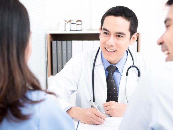 man and woman talking with doctor