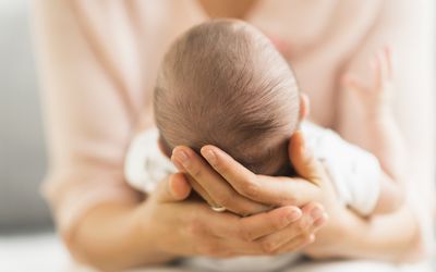 Rear view of a baby's head as he's being held