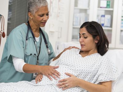 Black doctor examining pregnant patient's belly
