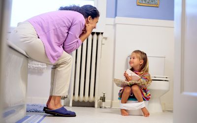 Girl reading a book on a potty chair