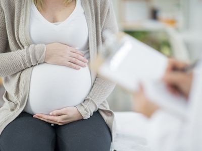 Pregnant woman holding stomach in doctor's office