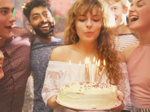 Woman blowing candles while celebrating birthday with friends