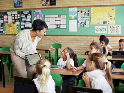 Teacher interacting with kids in class with tablet