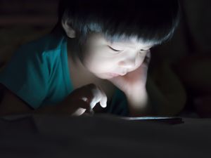 kid with tablet in the dark on bed and reading at Night .