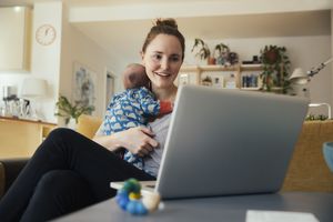 使用电脑时抱着新生儿的妇女