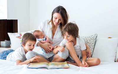 Mom reading to newborn and older kids