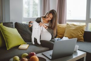 一位准妈妈在虚拟婴儿送礼会上向电脑展示婴儿服装