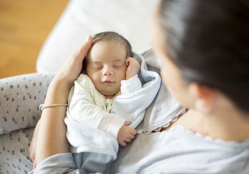 孩子在睡觉的时候睡着了。在蓝色的蓝色围巾上。妈妈在白米旁边的婴儿在一起。妈妈穿着灰色的灰色衬衫，发现了红色指纹