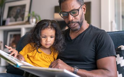 Father reading book with daughter during