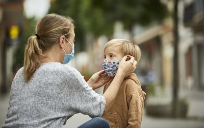 妈妈给她年幼的儿子戴上口罩