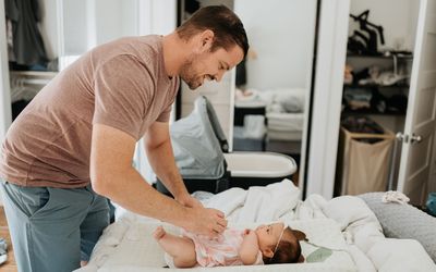 Father changing baby girl's diaper on changing table