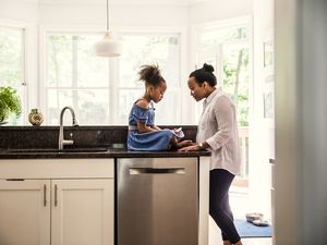 Mother and young daughter talking in kitchen