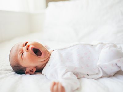 Baby girl yawning on bed