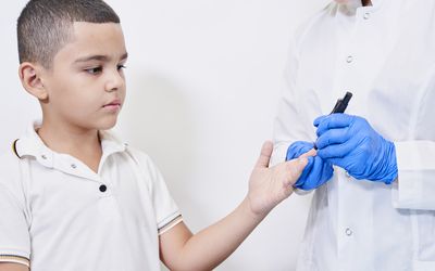 A nurse testing young boy for diabetes.