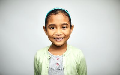 Young girl in green sweater smiling at the camera