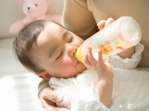 母亲抱着喝奶瓶的女儿(6-9个月)