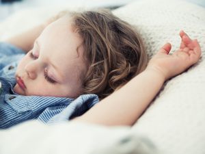 睡觉的蹒跚学步的男孩，手臂放在枕头上