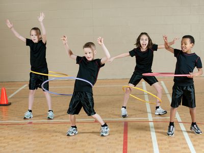 Kids in school gym playing with hula hoops
