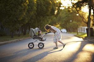 母亲和儿子推着婴儿车在夕阳下散步