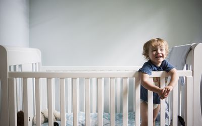 toddler standing and smiling in crib