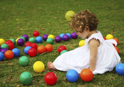 小女孩拿着五颜六色的塑料玩具球