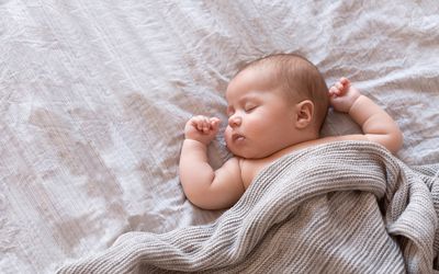 Peaceful baby lying on a bed and sleeping at home