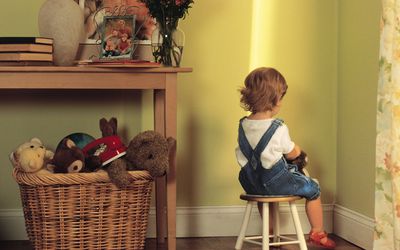 Young child sitting in corner as punishment