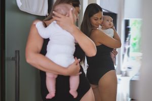 妇女抱着婴儿看产后的身体