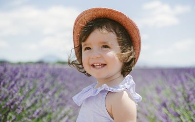 戴着帽子的小女孩站在一片紫色的花地里