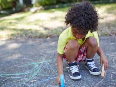 Large motor skills activities: Boy drawing with sidewalk chalk