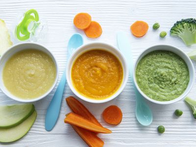 An assortment of organic baby foods on a painted wood surface