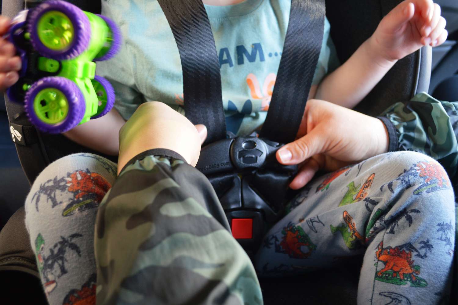 Person adjusting the seat belt for a child sitting in the Graco Turn2Me 3-in-1 Rotating Convertible Car Seat