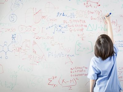 Schoolgirl in front of wipe board, math equations